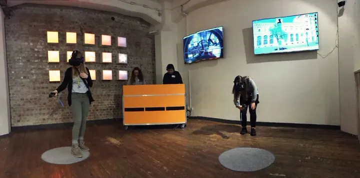 Visitors with VR headsets in the exhibition room, a supervisor at a desk