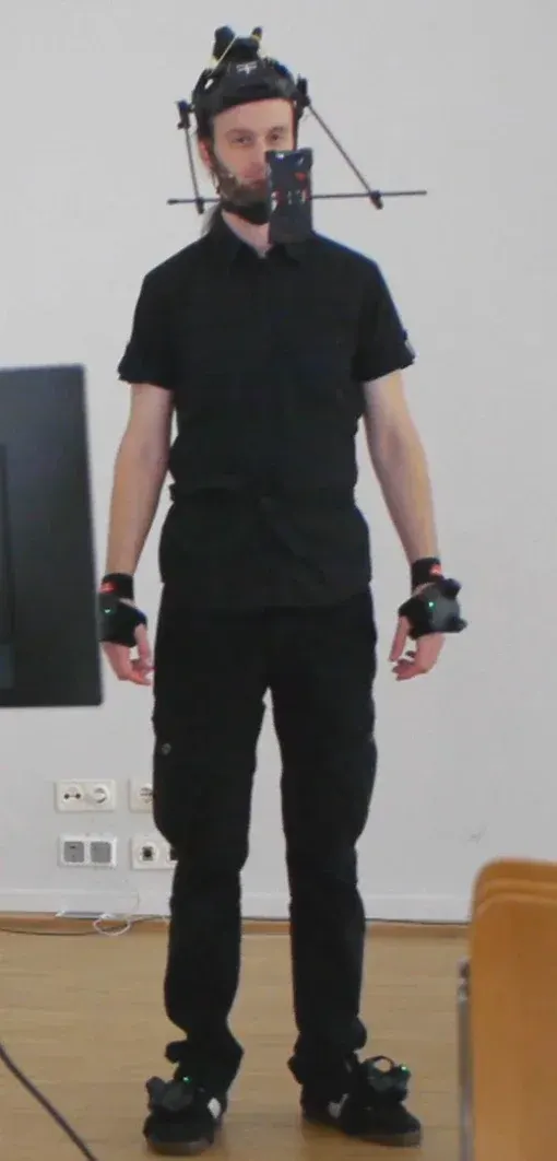 Performer in a motion capture suit with a head-mounted facial capture rig